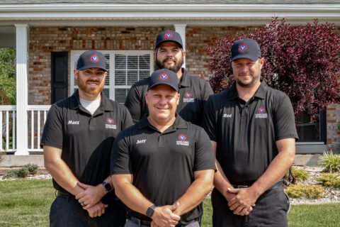 Four men in black shirts stand before the house, representing Vogelsang Pest Management in O’Fallon.